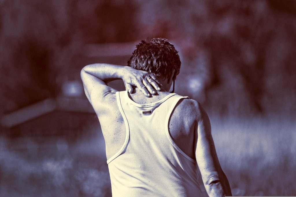 Rear view of a person stretching their neck while walking outdoors for daily health and exercise