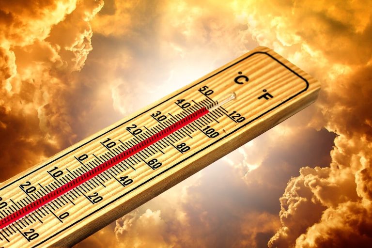A wooden outdoor thermometer showing high temperatures reaching 40 degrees Celsius against a dramatic golden and cloudy sky, representing the intense heatwaves caused by the El Nino climate pattern.