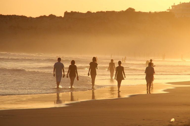 A group of people fast walking on a beach during a golden sunrise.