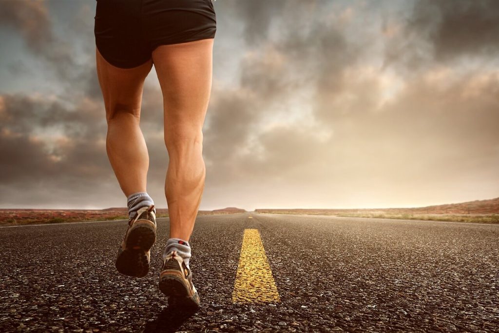 Close-up of legs jogging on an empty asphalt road during sunset for heart health