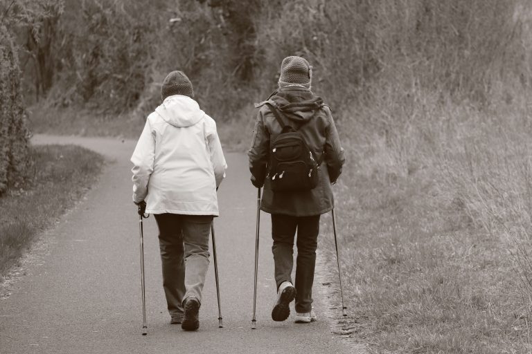 Two elderly people walking with nordic poles to manage arthritis pain